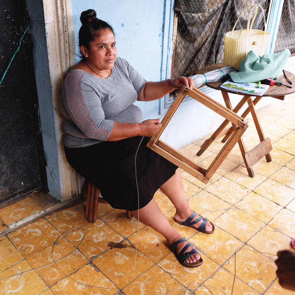 Female artisan is weaving a handmade basket in El Salvador